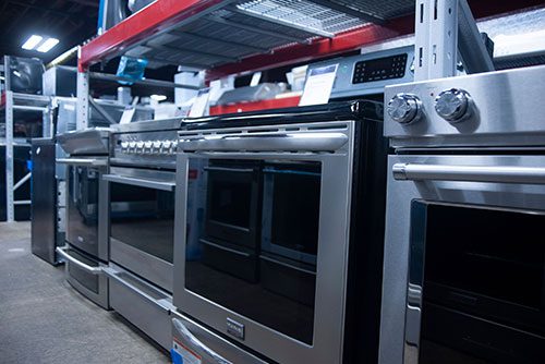 A close-up of a gas range with an oven displayed in a row inside an appliance store.